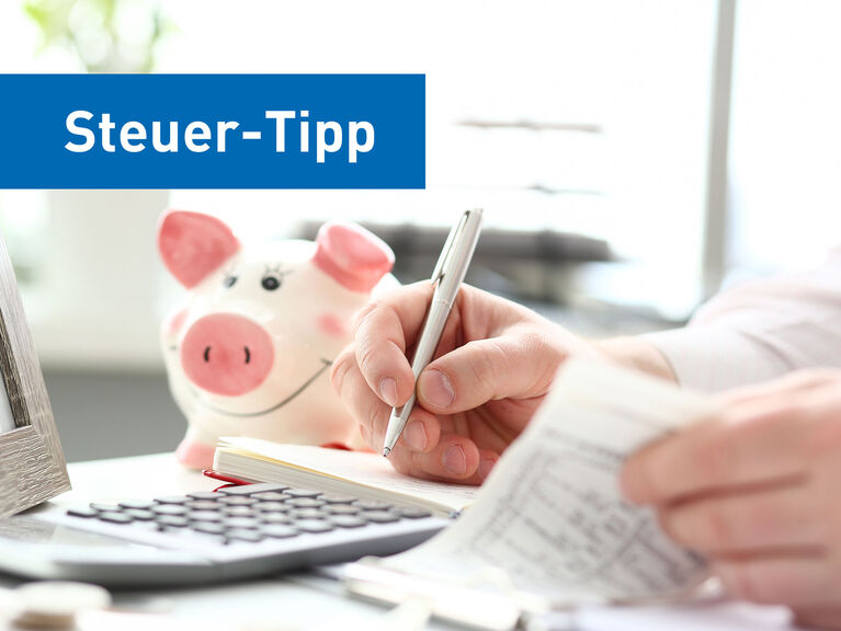 Bildausschnitt eines weißen Schreibtischs, Hände eines Mannes blättern durch Notizen und schreiben mit einem Kugelschreiber. Bilderrahmen, Sparschwein, Taschenrechner befinden sich neben den Händen auf dem Tisch Bildausschnitt eines weißen Schreibtischs, Hände eines Mannes blättern durch Notizen und schreiben mit einem Kugelschreiber. Bilderrahmen, Sparschwein, Taschenrechner befinden sich neben den Händen auf dem Tisch