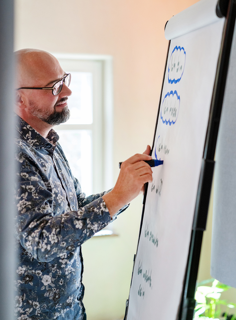 Sven Bartosch schreibt stehend auf weißes Flipchart