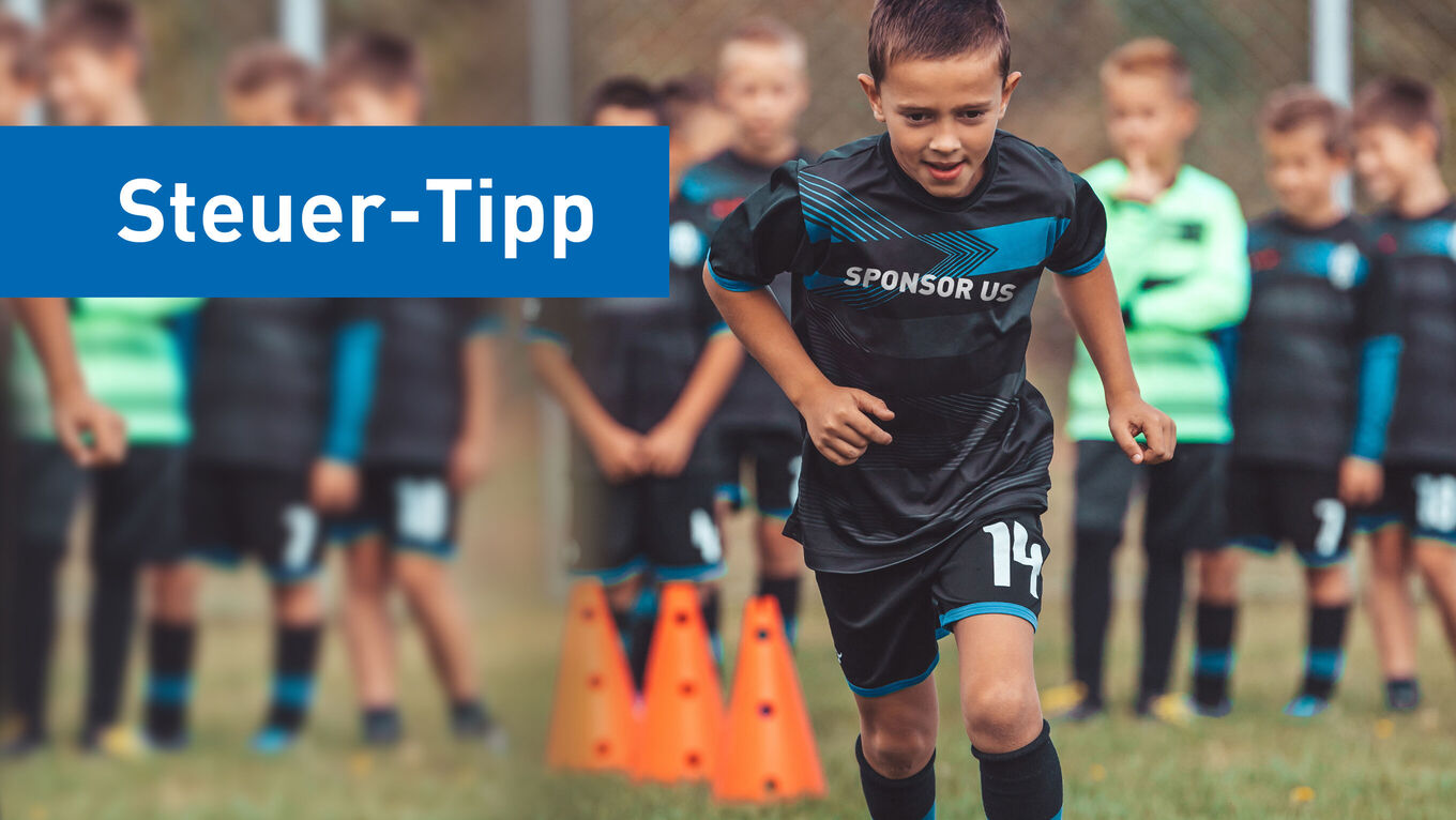 Gruppe von Grundschuljungs macht Lauftraining auf Rasenfußbalplatz, ein Junge im Fokus hat den Schriftzug "sponsor us" auf dem Trikot