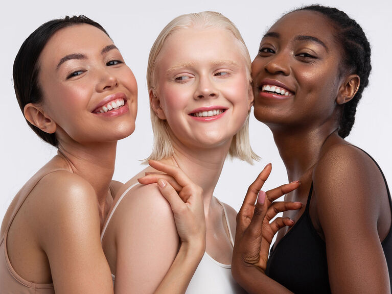 Drei lächelnde Frauen mit unterschiedlichen Hauttönen