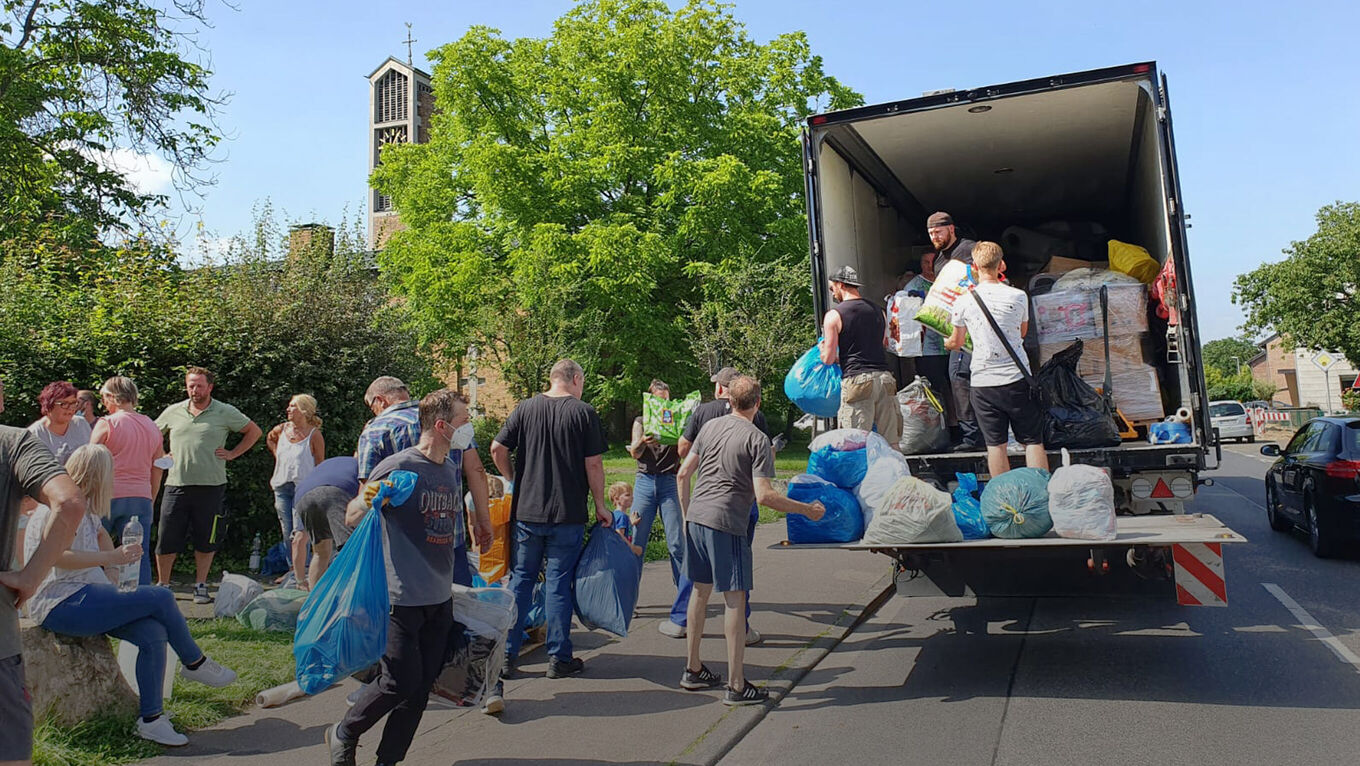 Helfer tragen Tüten und Pakete zu einem LKW