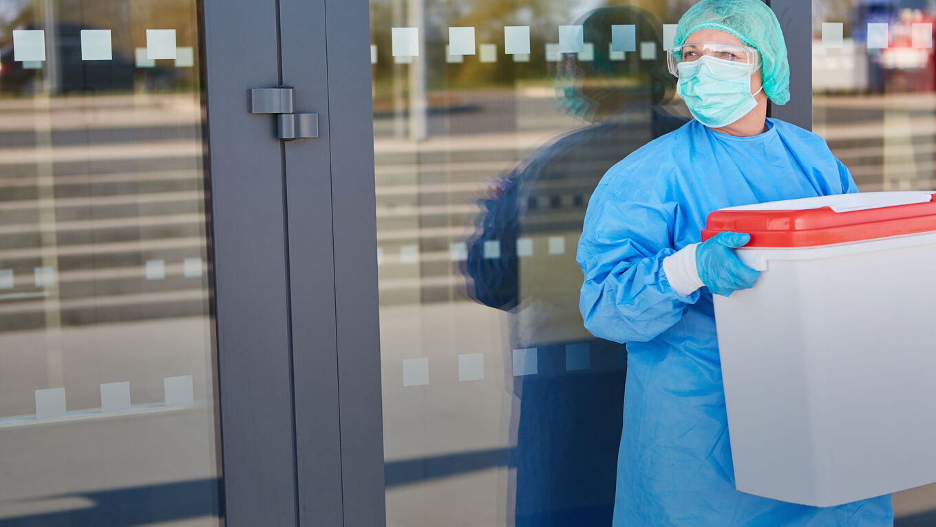 Arzt in OP-Kleidung mit Organspendebehälter
